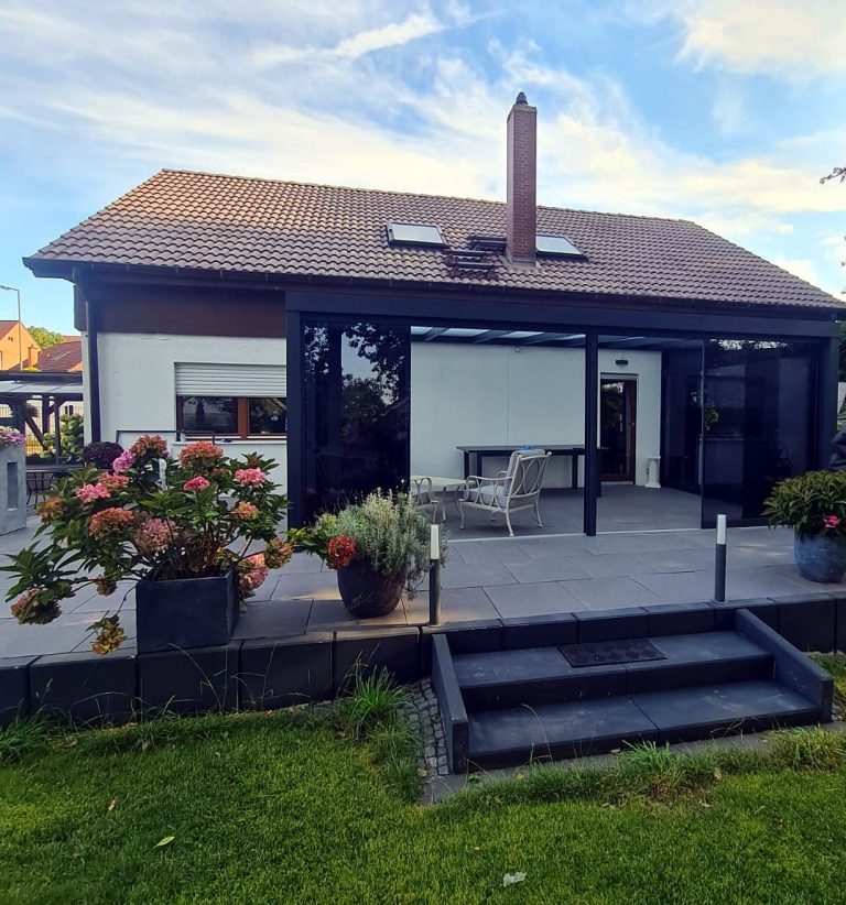 Fertiger Glas-Terrassenraum an einem Einfamilienhaus mit Stufen in den Garten