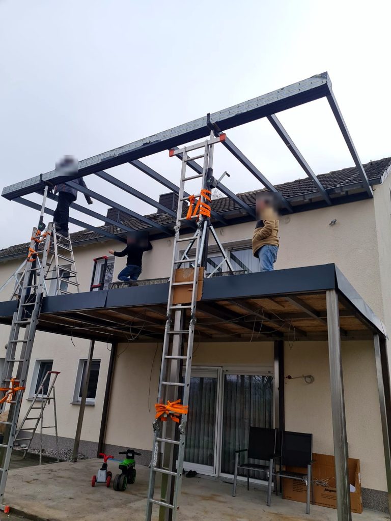 Monteure setzen die Dachsparren einer Überdachung über einem Balkon