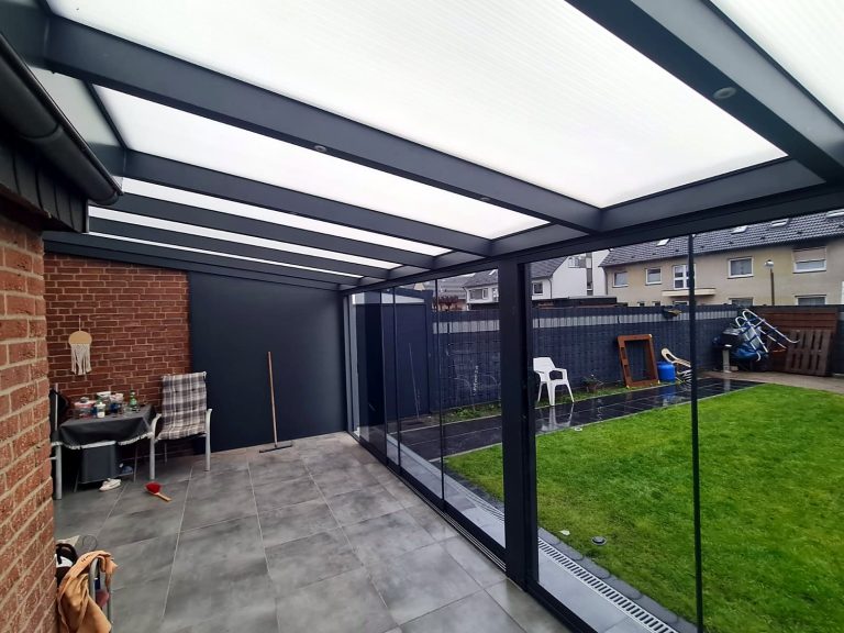 Terrassenraum mit lichtdurchlässigem Dach und Glasschiebewänden, Blick in den Garten