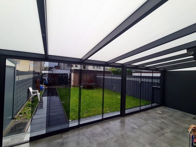 Innenansicht eines Terrassenraums mit Milchglasdach und Glasschiebewänden zum Garten