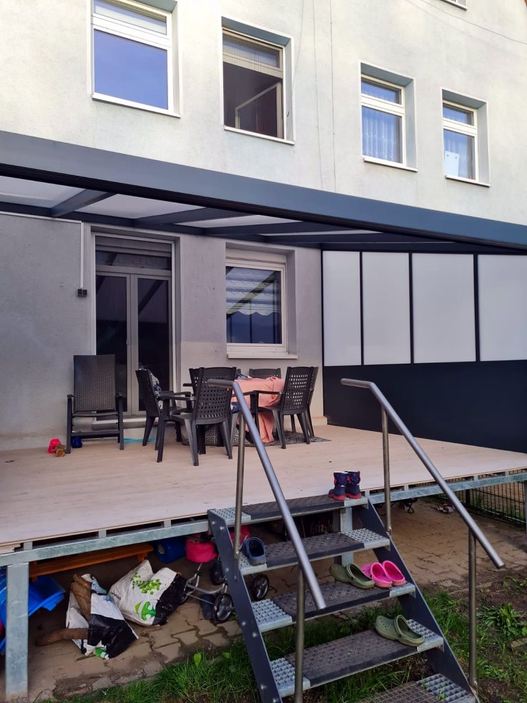 Terrassenüberdachung über einer erhöhten Terrasse mit Sichtschutz-Seitenwand