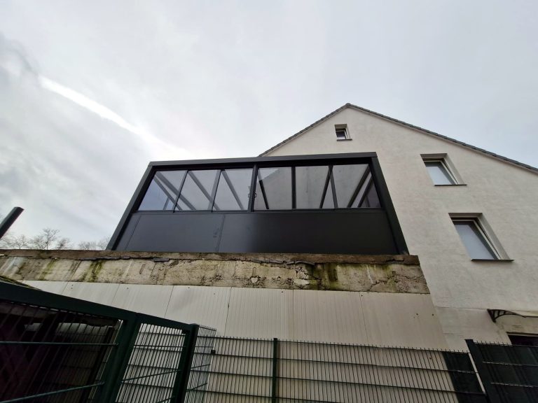 Verglaster Anbau mit anthrazitfarbenem Rahmen am Obergeschoss eines Hauses